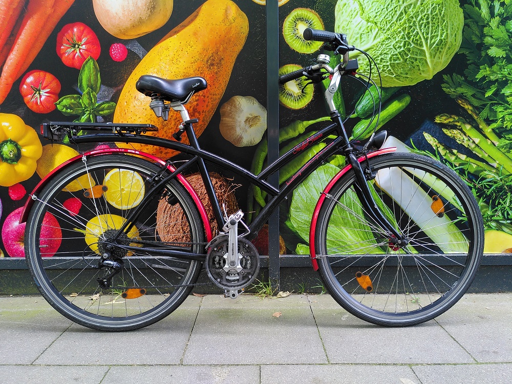 Fahrrad mit Futura Rahmen vor Fotowand mit buntem Gemüse und Gemüse